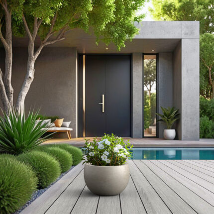KANTE weathered concrete bowl planter with white flowers on a poolside deck.